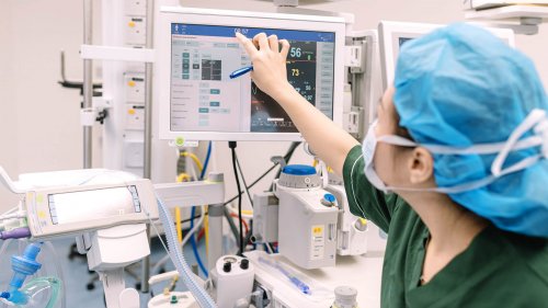 an asian chinese Anesthetist Working In Operating Theatre checking on monitor an asian chinese Anesthetist Working In Operating Theatre